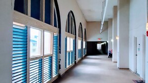 A long, narrow hallway with arched windows and a concrete floor. - Cozy Beach Condo with Private Beach, heated pool, High Speed WiFi, and More. (Orange Beach)