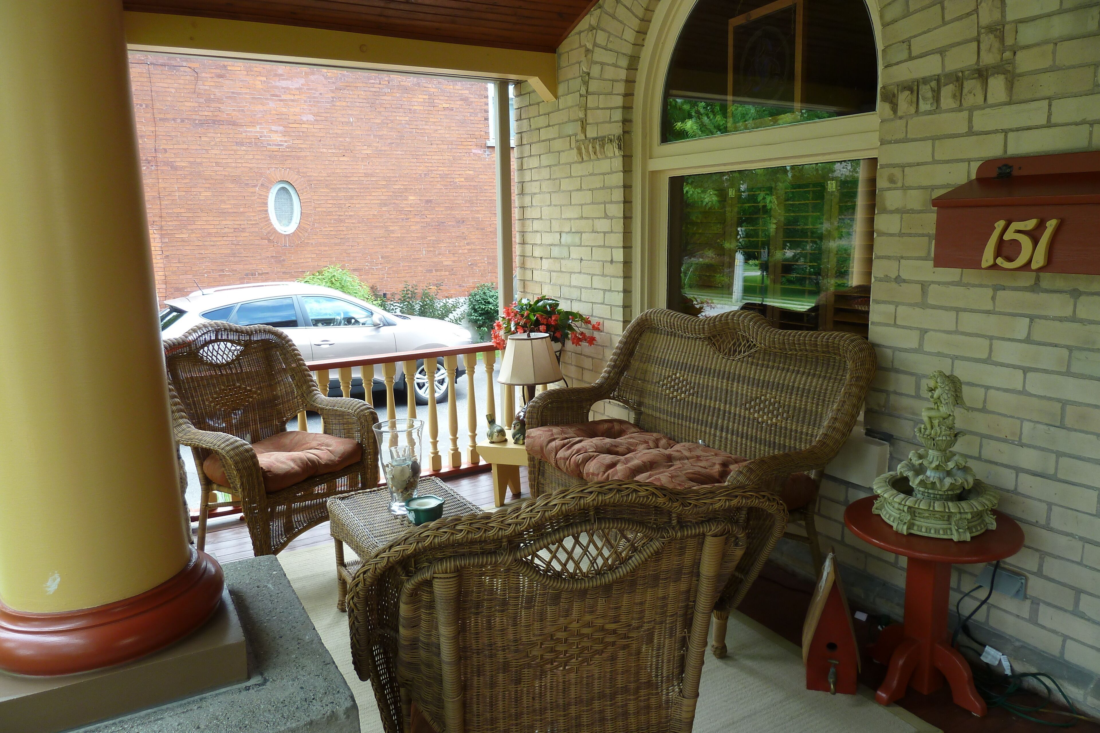A porch with wicker furniture, a mailbox, and a brick wall.