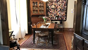 Un comedor con mesa de madera, sillas, una araña y un papel tapiz estampado.