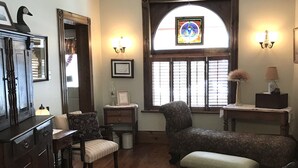 Un salón acogedor con suelo de madera, un ventanal con diseño de vitral, chimenea y un espacio de estar cómodo con sofá y sillones.