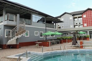 Ein Hotel mit Pool, Außenbereich und einer Treppe zu einer oberen Ebene.