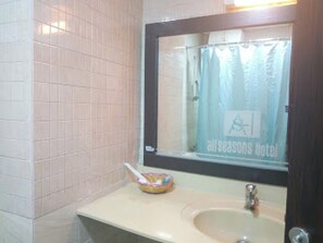 A bathroom with a sink, mirror, and a window with a curtain.
