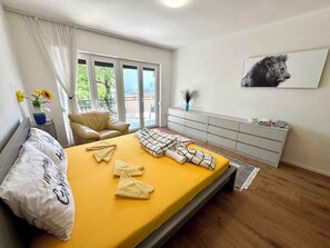 A bedroom with a bed, a sofa, a dresser, and a window with a view.