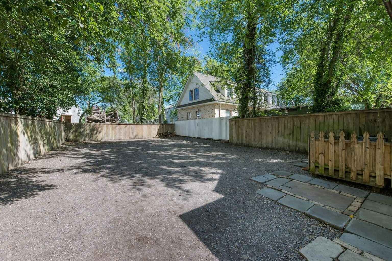 A fenced backyard with a gravel path leading to a house.