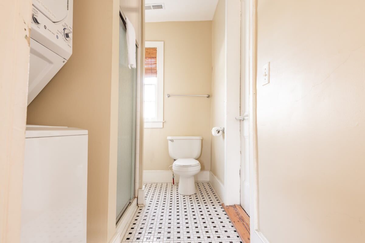 Un baño pequeño con inodoro, zona de ducha y lavadora.