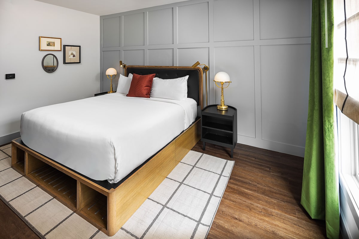A neatly arranged bedroom with a bed, bedside tables, and a window with curtains.