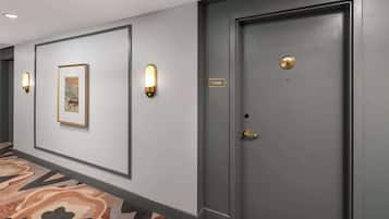 A hallway with a framed map on the wall, a door with a brass handle, and a light fixture.