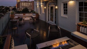 A rooftop terrace with a fire pit, seating area, and a view of a cityscape at dusk. - Wylie Hotel Atlanta, Tapestry Collection by Hilton (Atlanta)