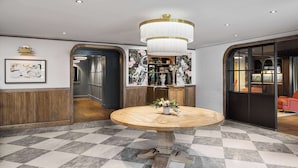 A lobby with a checkered floor, a round wooden table with a vase, and a chandelier. - Wylie Hotel Atlanta, Tapestry Collection by Hilton (Atlanta)