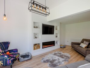 A modern living room with a fireplace, a mounted TV, and a cozy seating area.