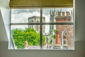 Una ventana con vistas a un edificio histórico de múltiples torres y una chimenea de ladrillo.
