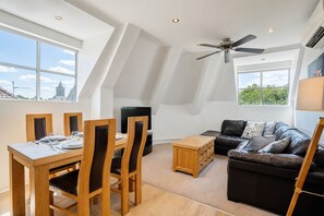 Een moderne loft met een woonruimte, een eethoek, een bank en een plafondventilator.