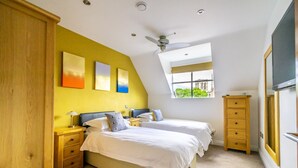 A bedroom with two beds, a ceiling fan, a window with a view, and a TV. - 7 Aspire -  a family break that sleeps 4 guests  in 2 bedrooms (York)