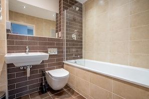 Une salle de bain moderne avec un lavabo, des toilettes et une baignoire, le tout de couleur blanche.