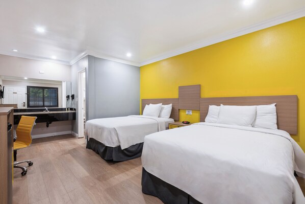A hotel room with two beds, a desk, and a chair.