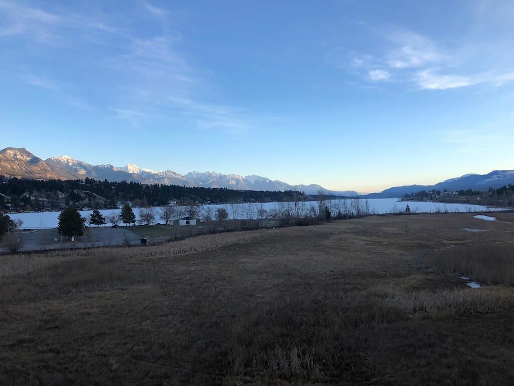 Un campo amplio y abierto con un lago y montañas al fondo.