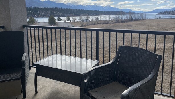 A balcony with a table and chairs, overlooking a lake and mountains. - Top floor condo on Lake Windermere with spectacular lake and Mountain View’s (Invermere)