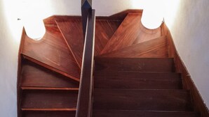 Una escalera de madera con barandilla central y dos apliques a cada lado.