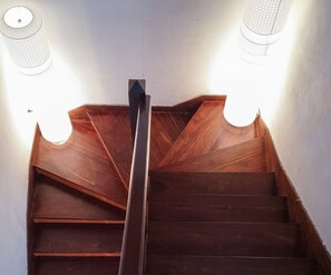 A wooden staircase with a central handrail and two wall-mounted light fixtures on either side.