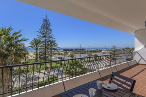 Ein Balkon mit Blick auf einen Parkplatz, Palmen und einen wolkenlosen, blauen Himmel.