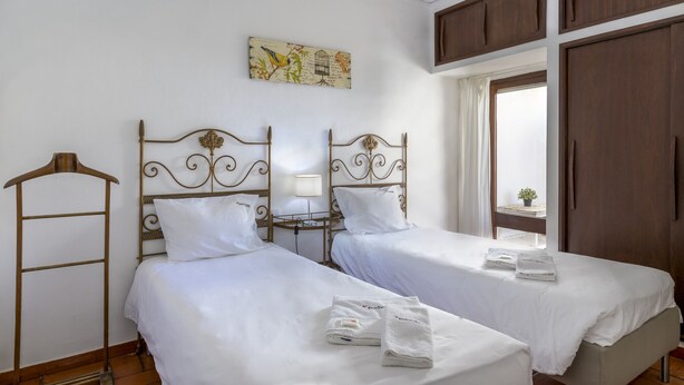 Habitación de hotel con dos camas, un armario, una ventana con cortinas y una obra de arte colgada en la pared.