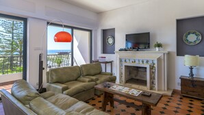 Una sala de estar con sofá, mesa de centro, chimenea y televisor.