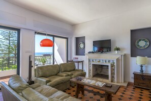 A living room with a sofa, a coffee table, a fireplace, and a television.