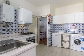 Eine kompakte Küche mit Gasherd, weißen Schränken, einer Waschmaschine und backsplash-Fliesen mit Muster.
