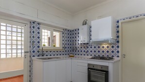 Una cocina con armarios blancos, estufa, horno y ventana con vistas.