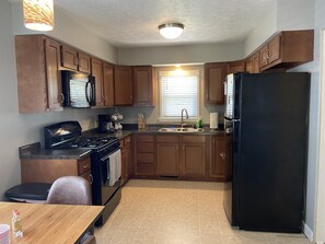 Compact kitchen with gas stove, microwave, and sink, offering a convenient space for meal preparation.