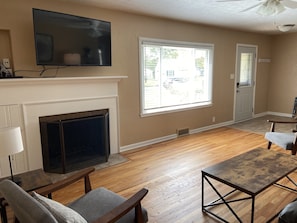 Relax in this stylish living room with a large flat-screen TV above the fireplace, a comfortable seating area, and a beautiful view.