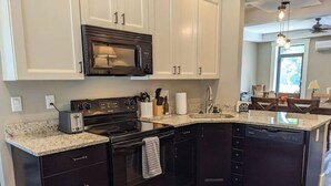 A modern kitchen with dark cabinetry, a black microwave, a stove, and a dishwasher.