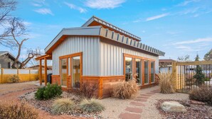 A modern house with a sloped roof, large windows, and a stone pathway leading to the entrance. - Luxe stay in Kanab with stargazing rooftop deck, pool & hot tub (Kanab)