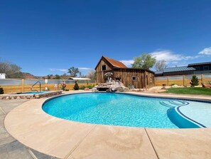 Une piscine avec, en arrière-plan, une structure en bois évoquant une grange.