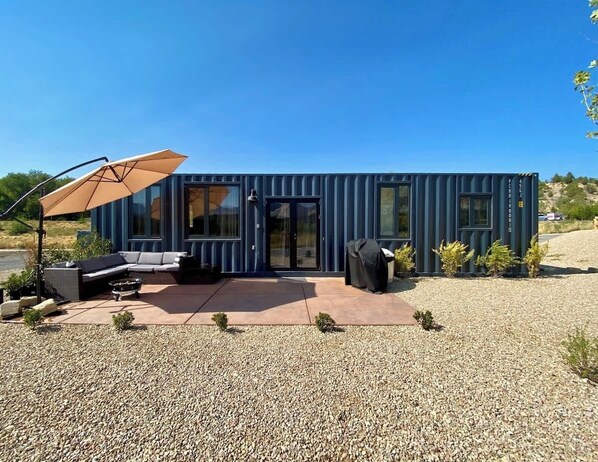 Une maison moderne préfabriquée, dotée d’une terrasse, d’un espace salon extérieur et d’une zone couverte.