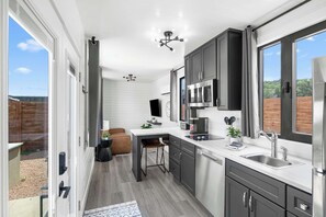 A modern kitchen with a large window, a dining area, and a built-in TV.