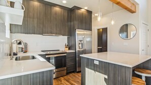 Una cocina moderna con armarios de madera oscura, electrodomésticos de acero inoxidable y una isla central con taburetes.