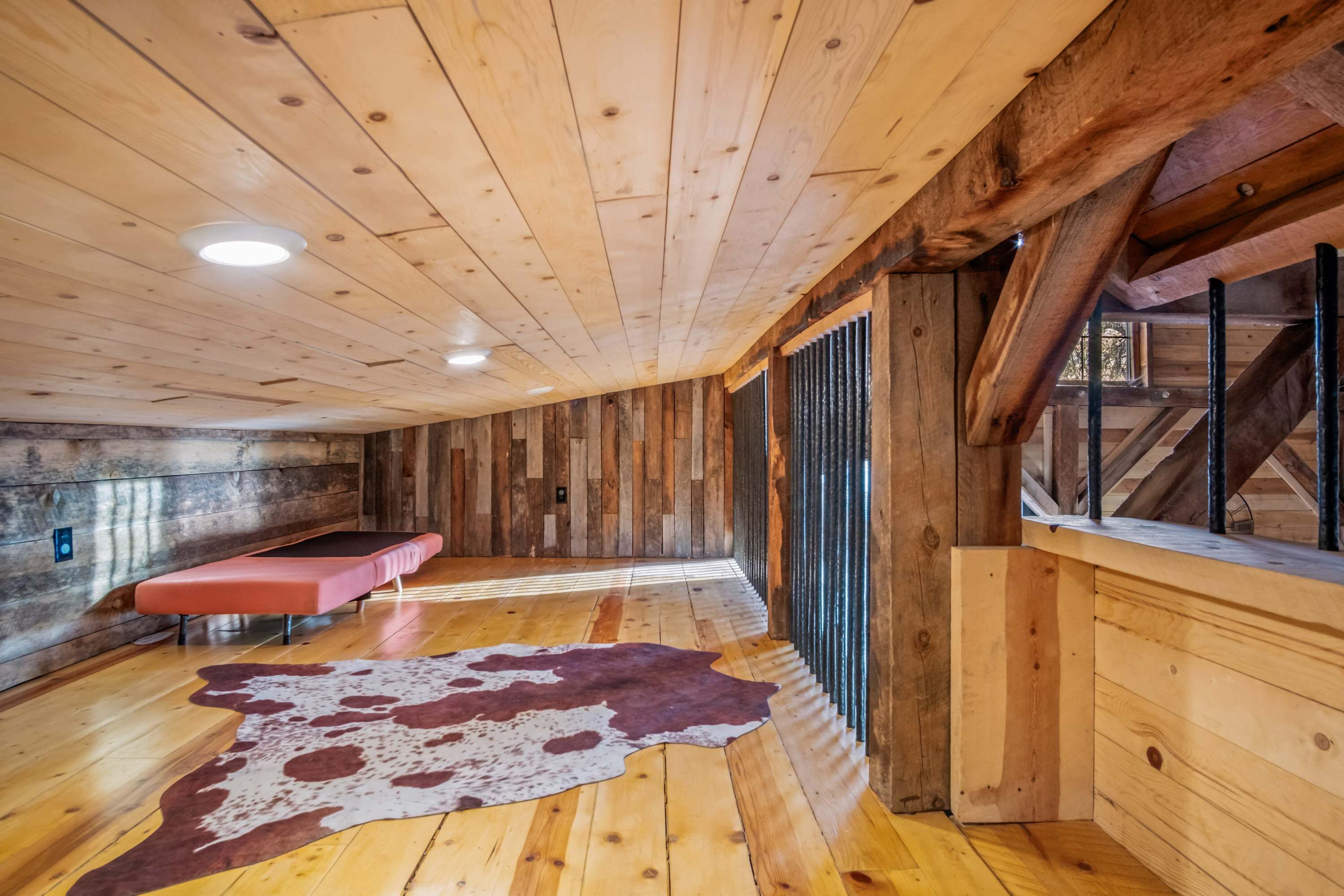 A wooden interior with a bench, a cowhide rug, and a window with a view.