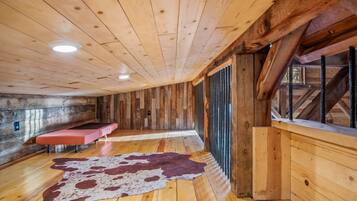 A wooden interior with a bench, a cowhide rug, and a window with a view.