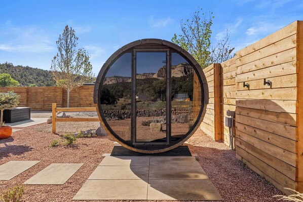 A circular structure with a glass door, surrounded by a gravel path and wooden fencing.