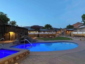 A pool area with a wooden building and a covered patio.
