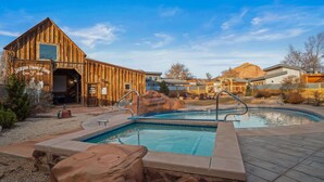 Un edificio rústico de madera con zona de piscina, que incluye un jacuzzi y un área de estar de piedra.