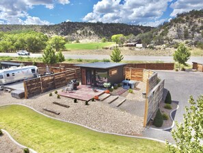 A modern RV park with a small cabin, outdoor seating, and a gravel driveway. - East Zion Designer Container Studio- The Fields (Orderville)