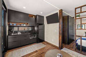 A modern kitchen with dark cabinetry, a built-in oven, and a microwave. - East Zion Designer Container Studio- Satori Zion (Orderville)