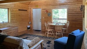 Een houten chalet van binnen, met een eethoek, een deur en een raam.