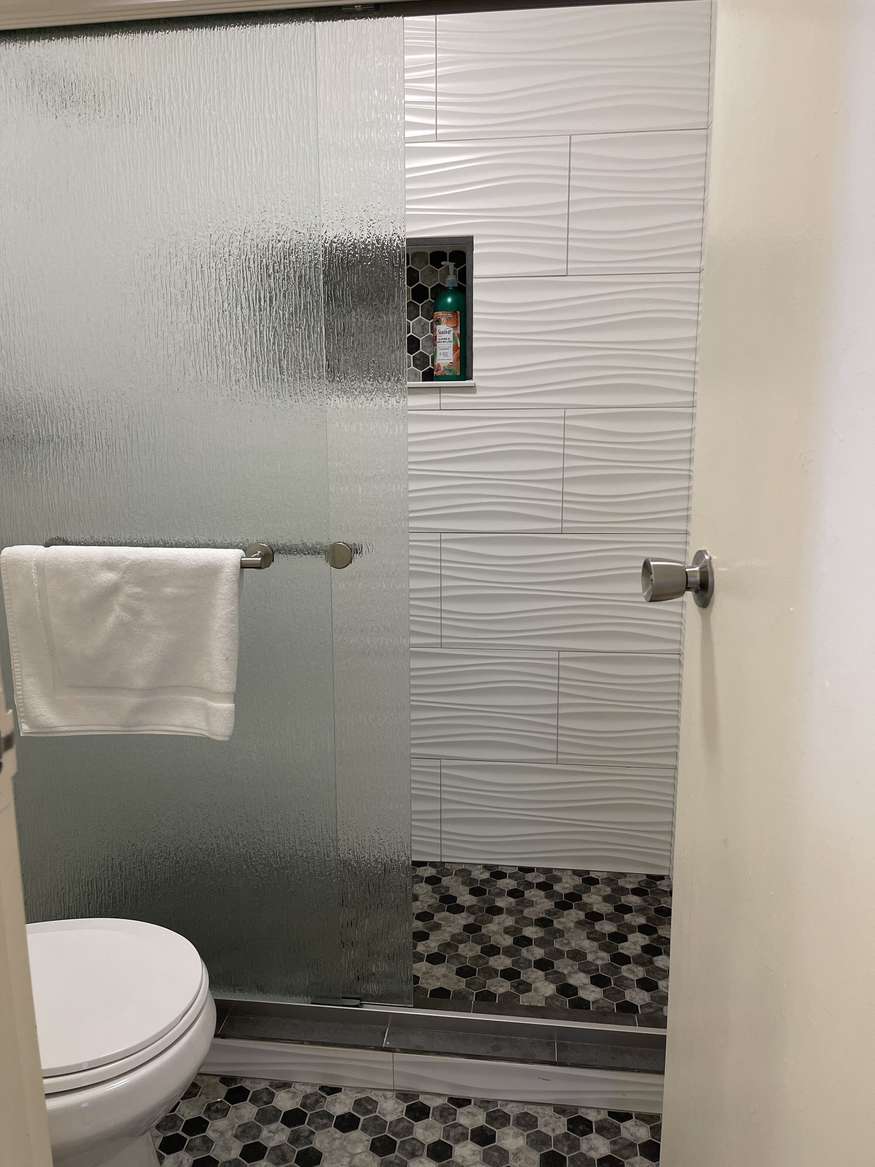 Une salle de bain équipée de toilettes, d’une douche à parois de verre et d’un porte-serviettes.