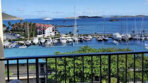 A marina with multiple boats docked, a building with a red roof, and a clear blue sky. - Sapphire Beach Villa (St. Thomas)