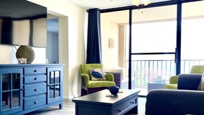 A modern living room with a blue cabinet, a green armchair, a black coffee table, and a view of the outdoors through a large sliding door. - Sapphire Beach Villa (St. Thomas)