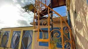 Ein gelbes Gebäude mit einer Wendeltreppe und einem Fenster mit blauer Umrandung.