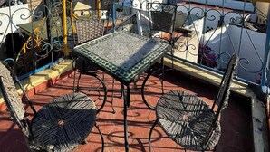 Eine Dachterrasse mit Tisch und Stühlen und Blick auf die Stadtlandschaft unter einem wolkenlosen Himmel.